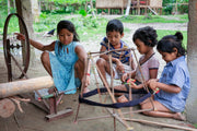 Children operating a traditional weaving loom together