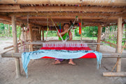 Woman weaving fabric on a traditional loom.