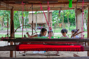 Children learning to weave on a traditional loom.