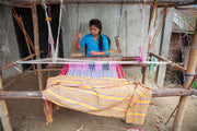 Woman weaving fabric on a traditional loom.