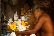 Man crafting small statues in a workshop
