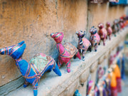 Row of colorful handmade camel toys on a ledge