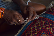 Hands of a person weaving a colorful rug
